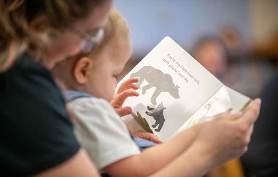 A parent reading a picture book with their toddler at story time